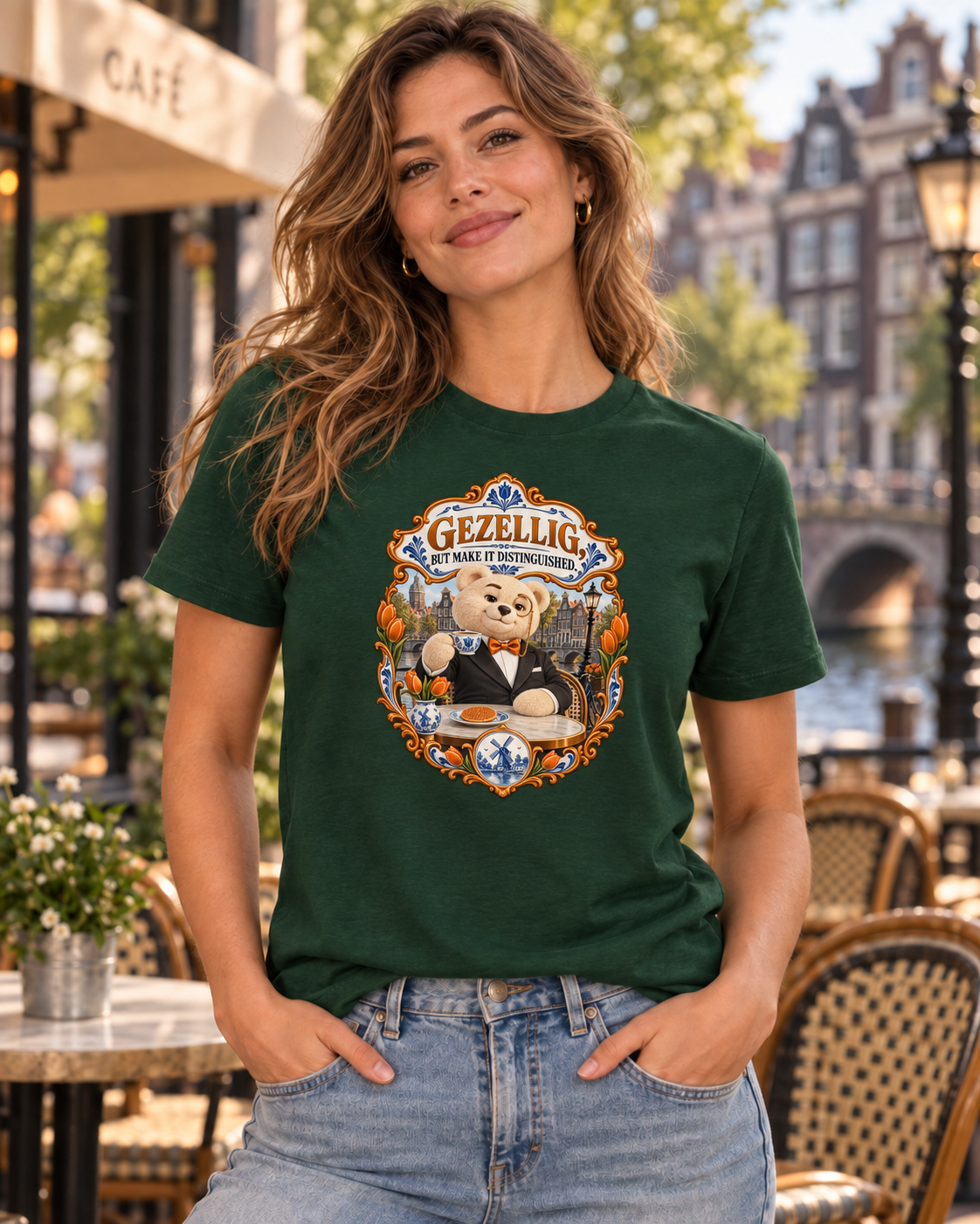 Olive T-shirt featuring Teddy O’Broin wearing a tuxedo and monocle beside an Amsterdam canal with tulips, a Delft cup and stroopwafel beneath the words Gezellig, But Make It Distinguished.