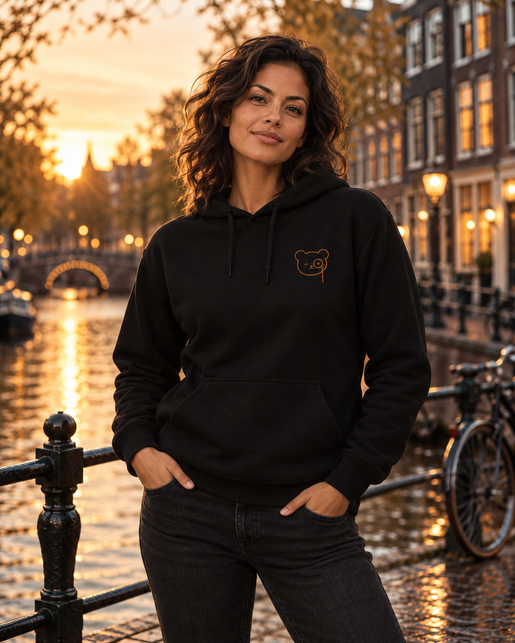 Black pullover hoodie with a small copper Teddy O’Broin bear-face emblem printed on the left chest.