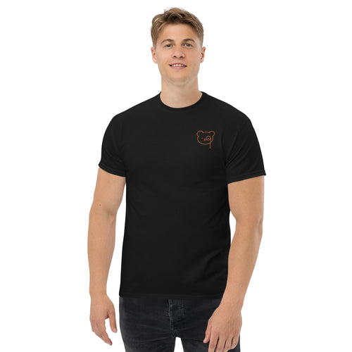Black T-shirt with a small copper Teddy O’Broin bear-face emblem printed on the left chest.